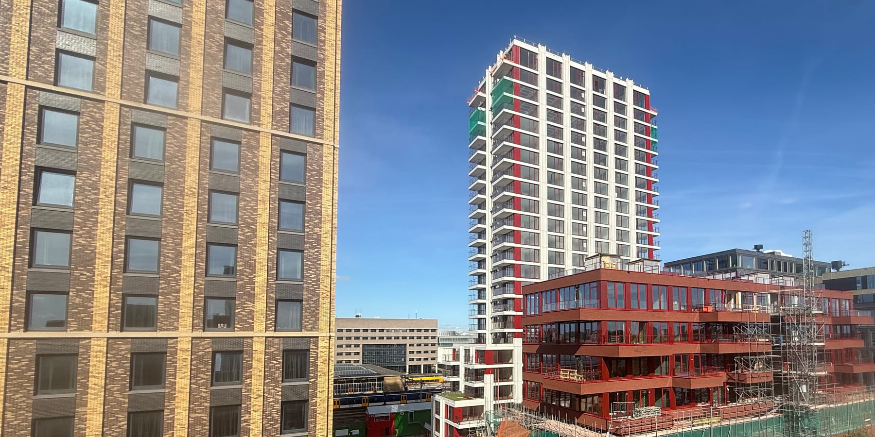 Woontorens in aanbouw in de steigers, naast een opgeleverde toren met rode accenten en een rij nieuwe appartementengebouwen: de bouwdelen waarvan een meerjarenonderhoudsplan het onderhoud vooruit plant